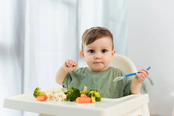 Toddler Boy Holding Spoon Looking Camera Vegetables High Chair — Stock Photo, Image