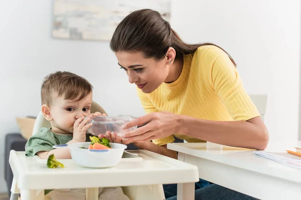 Toddler Fiú Ivóvíz Közelében Anya Élelmiszer Etetőszéken — Stock Fotó