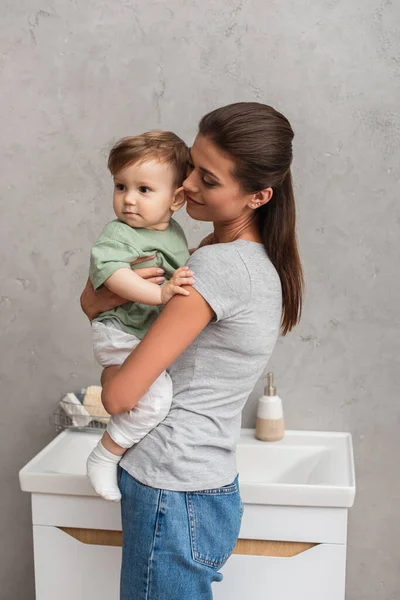 在浴室抱小孩的年轻女人 — 图库照片