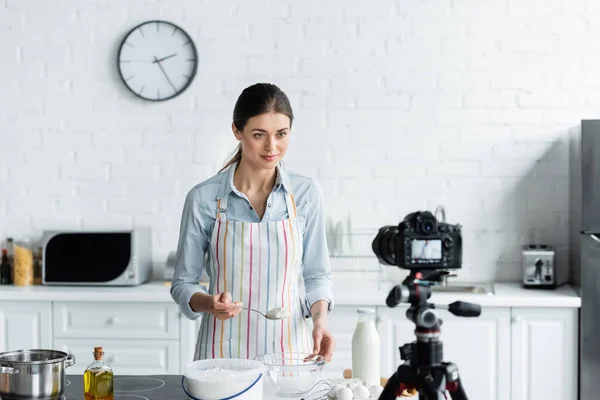 Молодой Кулинарный Блоггер Держит Ложку Мукой Перед Размытой Цифровой Камерой — стоковое фото