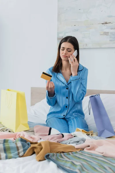 Ledsen Kvinna Silke Pyjamas Talar Mobiltelefon Samtidigt Som Kreditkort Nära — Stockfoto