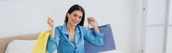 Happy Woman Silk Pajama Holding Shopping Bags While Smiling Camera — 图库照片