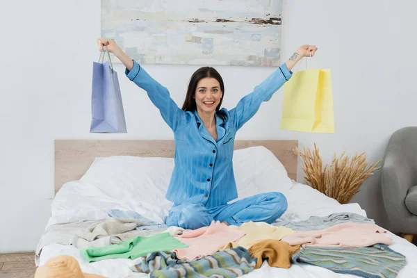 Fröhliche Frau Trendigen Pyjama Mit Einkaufstaschen Neben Kleidungsstücken Auf Dem — Stockfoto