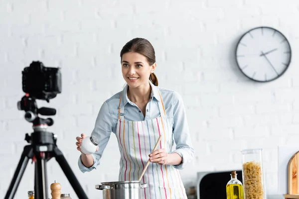 Smiling Woman Adding Salt Saucepan Front Blurred Digital Camera Kitchen — Stock Photo, Image