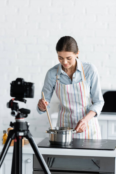 young culinary blogger preparing food in front of blurred digital camera