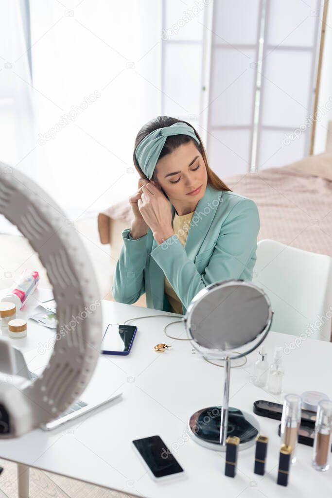 young beauty blogger preparing for record near phone holder and containers with cosmetics