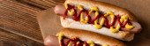 top view of tasty hot dogs with mustard and ketchup on wooden surface, banner