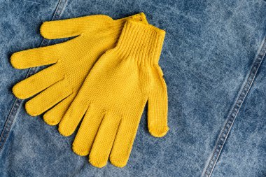 Mavi kot kumaş üzerine sarı iş eldivenlerinin üst görünümü, İşçi Bayramı konsepti
