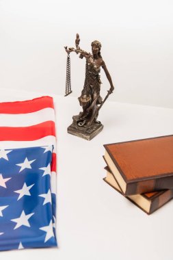 Amerikan bayrağı yakınındaki adalet heykelinin yüksek açılı görüntüsü ve beyaz üzerine izole edilmiş kitaplar.