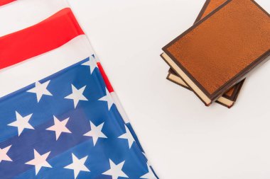 Beyaz üzerine izole edilmiş kitapların yakınındaki Amerikan bayrağının üst görünümü