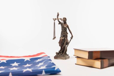 Amerikan bayrağının yanında adalet heykeli ve beyaz üzerine izole edilmiş kitaplar.
