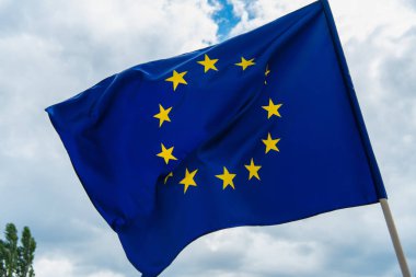 Gökyüzüne karşı sarı yıldızlı Avrupa Birliği bayrağının düşük açılı görüntüsü 