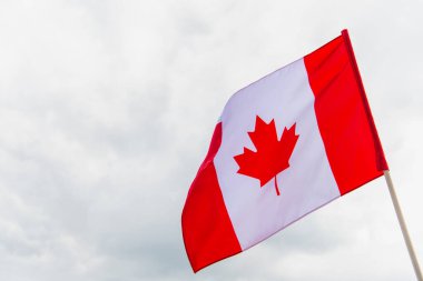 Kanada bayrağı ve akçaağaç yaprağı bulutlu gökyüzüne karşı 
