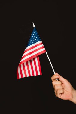 cropped view of patriotic man holding flag of america isolated on black