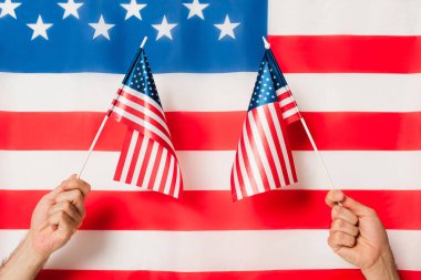 cropped view of patriotic men holding flags of america against american symbol