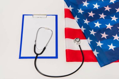 American flag near clipboard and stethoscope on white 