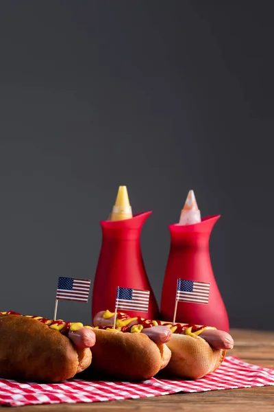 Verschwommene Saucenflaschen Und Hot Dogs Mit Kleinen Amerikanischen Flaggen Auf — Stockfoto