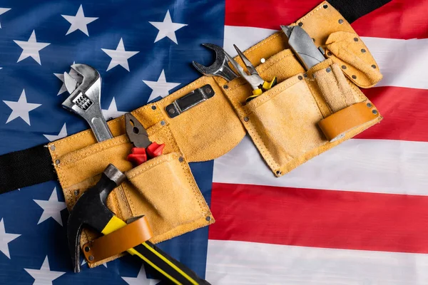 top view of leather tool belt with various tools on american flag, labor day concept