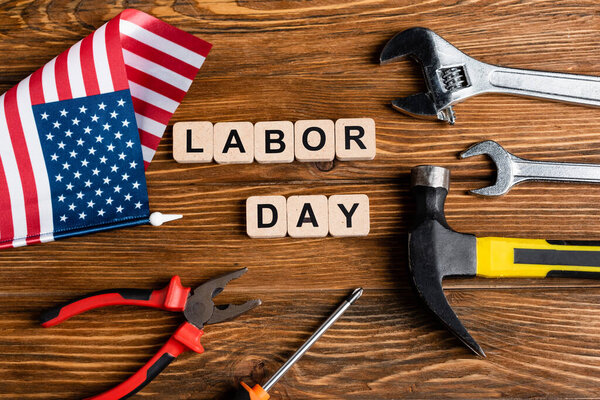 top view of cubes with labor day lettering near various tools and small usa flag