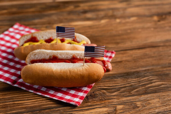 tasty hot dogs with small usa flags on wooden surface
