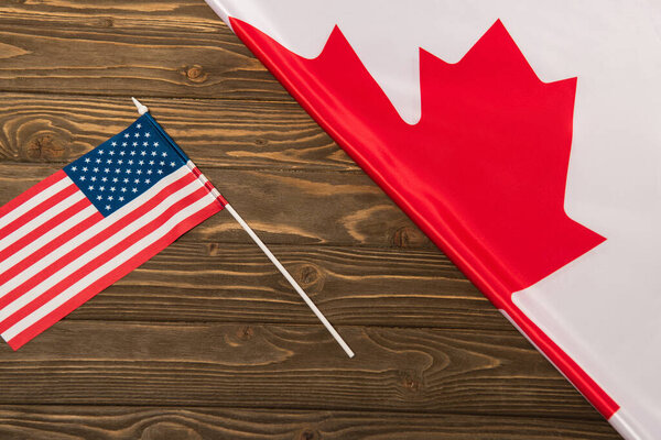 top view of canadian and american flags on wooden surface 