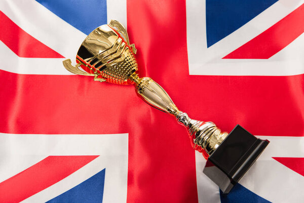 top view of golden trophy near national flag of united kingdom with red cross 