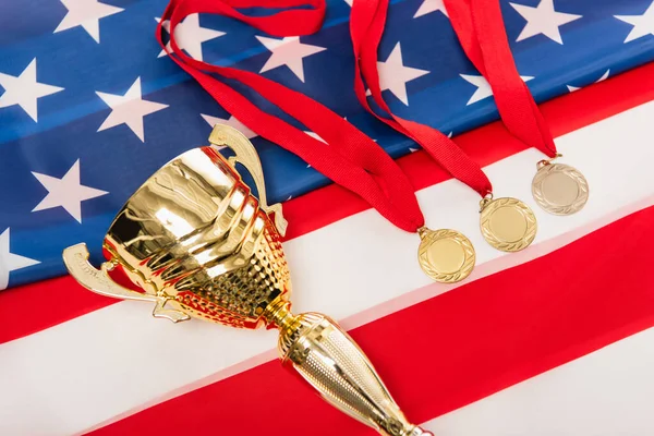 high angle view of golden medals and cup on american flag