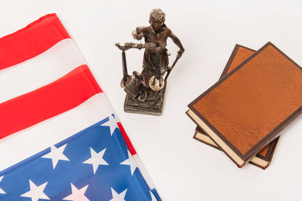 high angle view of statuette of justice near books and american flag isolated on white