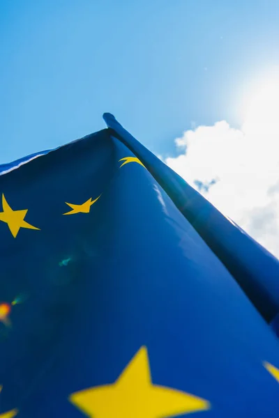 bottom view of blue european union flag against sky with clouds