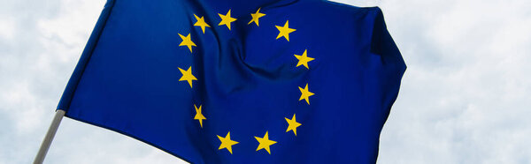 низкоугольный вид синего флага Европейского Союза на фоне неба, знамя
