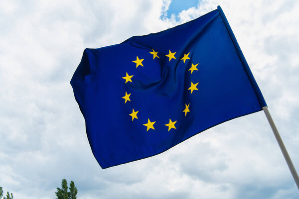 низкоугольный вид европейского флага союза, размахивающего на фоне неба 