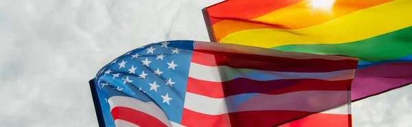 low angle view of american and lgbt flags against sky, banner