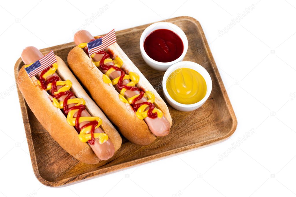 wooden tray with hot dogs and bowls with ketchup and mustard isolated on white