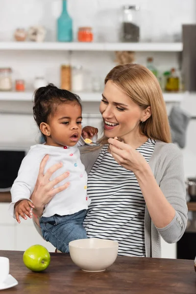 Fröhliche Mutter Füttert Adoptierte Afrikanische Amerikanische Tochter — Stockfoto