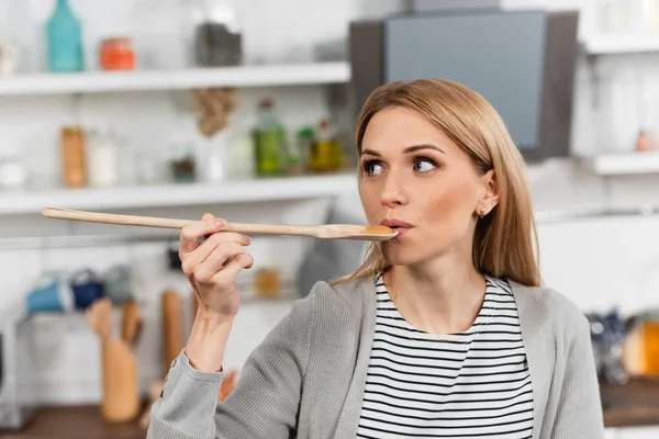 Mulher Segurando Colher Madeira Tentando Comida Enquanto Cozinha Cozinha — Fotografia de Stock