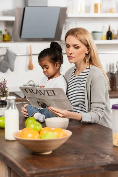 Mujer Leyendo Periódico Viaje Cerca Adoptado Afroamericano Hija Cocina — Foto de Stock