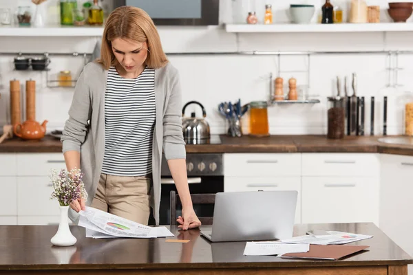 Ξανθιά Freelancer Κοιτάζοντας Διαγράμματα Ενώ Εργάζονται Από Σπίτι — Φωτογραφία Αρχείου