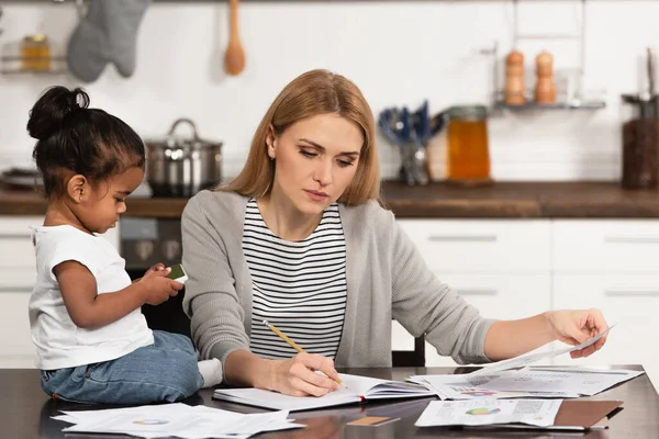Woman Writing Notebook While Working Home Adopted African American Daughter — Stock Photo, Image