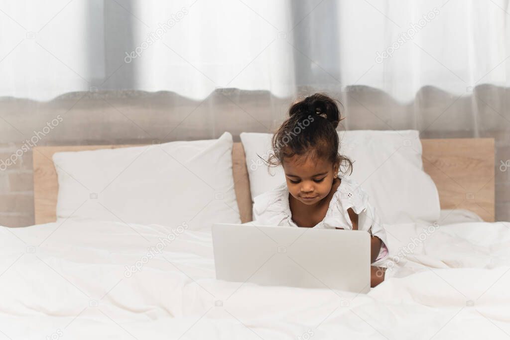 happy african american toddler kid using laptop in bedroom