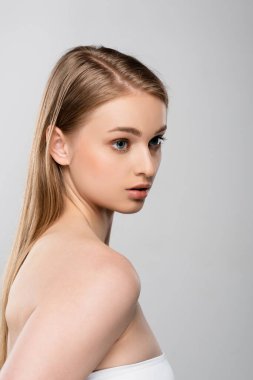 Çıplak omuzlu genç bir kadın, Gri üzerinde tek başına gözlerini kaçırıyor.