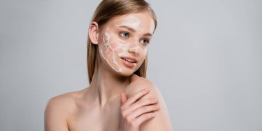 young woman with blue eyes and cleansing foam on face isolated on grey, banner clipart