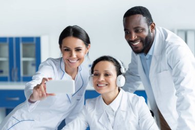 Klinikte bulanık akıllı telefon kullanan neşeli çoklu etnik doktorlar. 