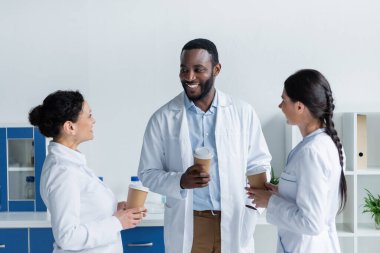 Klinikte kağıt bardak tutan çok ırklı doktorlar 