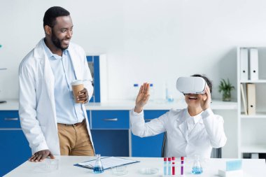 VR kulaklığı ve kahvesiyle laboratuarda neşeli Afro-Amerikan bilim adamları 