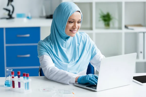 Cientista Árabe Positivo Usando Laptop Perto Tubos Ensaio Placas Petri — Fotografia de Stock