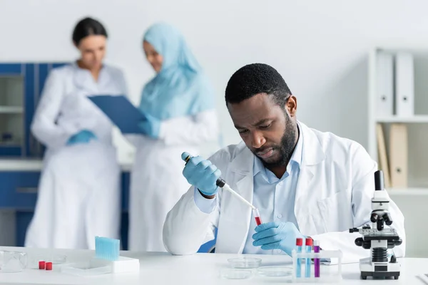 African American Scientist Researching Samples Test Tubes Blurred Colleagues Lab — Foto de Stock