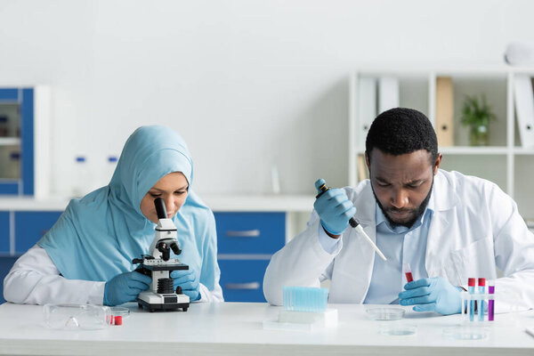 Мусульманские и африканские ученые изучают образцы в пробирках с помощью микроскопа 