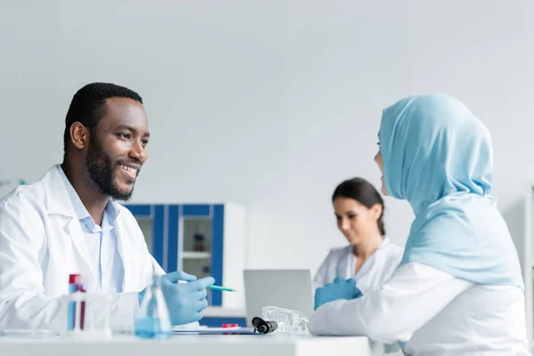 Cientista Afro Americano Sorrindo Para Colega Muçulmano Perto Equipamentos Laboratório — Fotografia de Stock