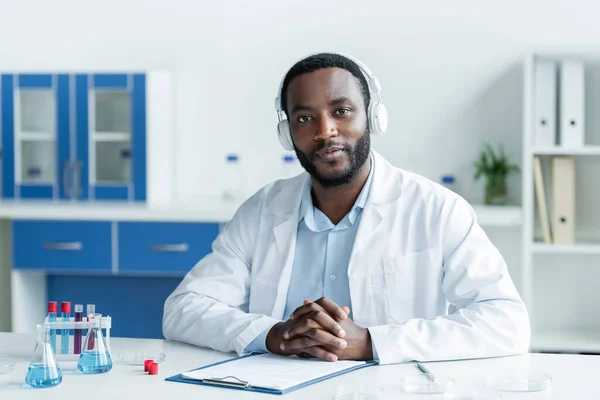 African American Scientist Headphones Looking Camera Flasks Clipboard — Foto de Stock