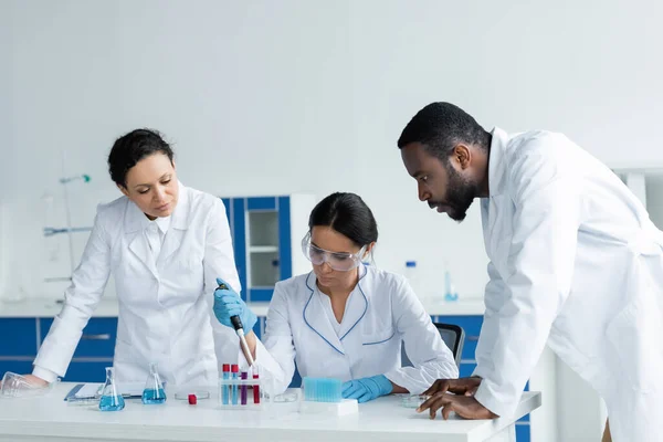 Laboratuvardaki Odaklanmış Meslektaşlarının Yanında Pipet Test Tüpleriyle Çalışan Bilim Adamı — Stok fotoğraf